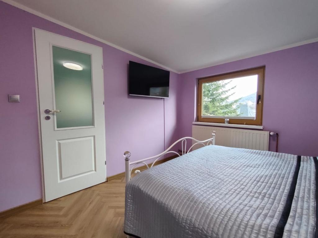 Apartament Centrum 2 Ustroń — fioletowa sypialnia z telewizorem i oknem