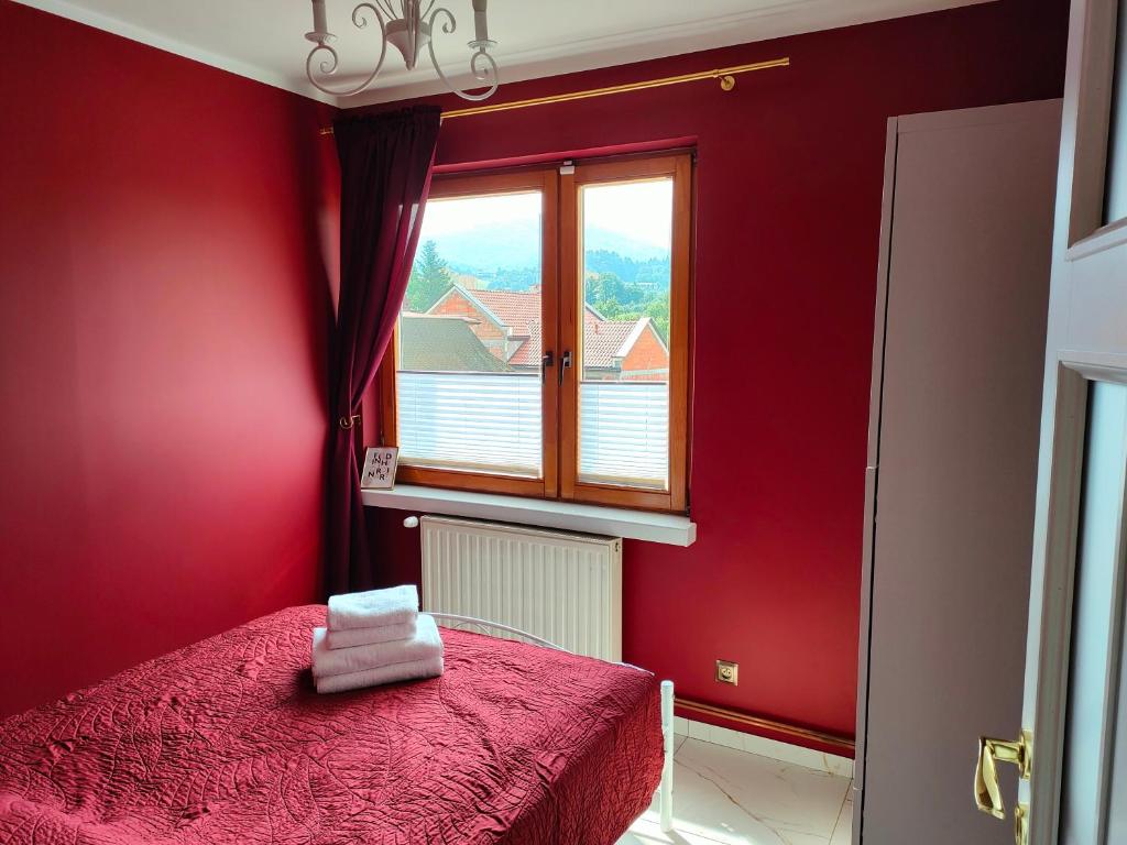 Apartament Centrum Ustroń — bordowa sypialnia z oknem i widokiem na góry